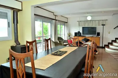 a dining room with a table and a living room at Casa con hermosa vista al lago in Villa Carlos Paz