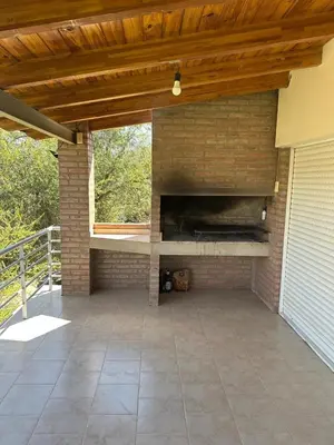 an outdoor patio with a brick fireplace and a wooden ceiling at Cabaña La Estancia in Villa Carlos Paz