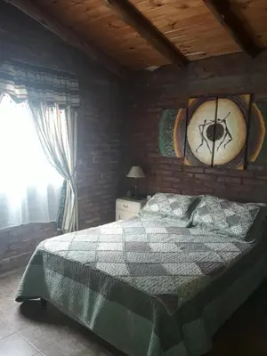 a bedroom with a bed and a clock on the wall at Cabaña La Pasionaria in Villa Quillinzo