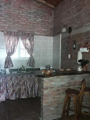 a kitchen with a sink and a brick wall at Cabaña La Pasionaria in Villa Quillinzo