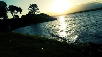 a body of water with the sun setting on the horizon at Cabaña La Pasionaria in Villa Quillinzo