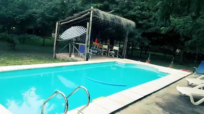 a large blue swimming pool with a gazebo at Cabaña La Pasionaria in Villa Quillinzo