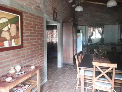 a kitchen with a table and a brick wall at Cabaña La Pasionaria in Villa Quillinzo