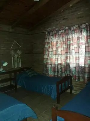 a bedroom with two beds and a window with curtains at Cabaña La Pasionaria in Villa Quillinzo