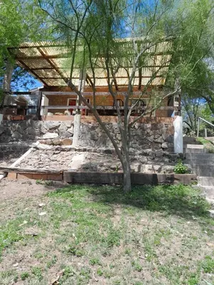 a house with a stone wall and a tree at La Loma in Villa del Dique