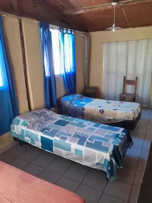 two beds in a room with blue curtains at La Loma in Villa del Dique