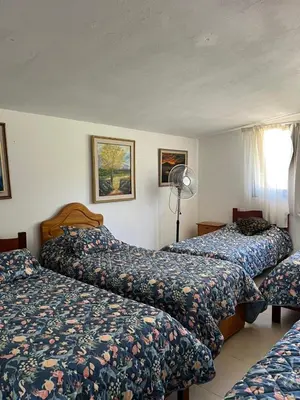 a hotel room with two beds and a fan at Casa Edison in Villa Carlos Paz