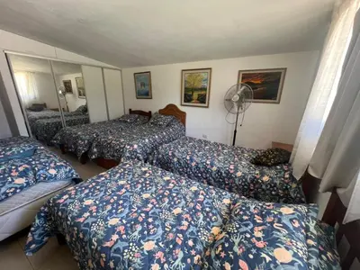 a hotel room with three beds and a fan at Casa Edison in Villa Carlos Paz