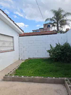 a white brick wall next to a green yard at La Bernardina in Villa Carlos Paz
