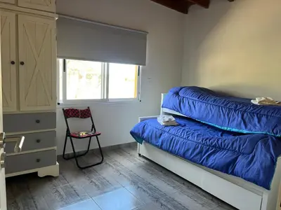 a bedroom with a bed with blue sheets and a chair at La casita de Clau in Los Molles