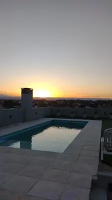 a swimming pool on the roof of a house with the sunset at Departamento céntrico a cuadras del lago san roque in Villa Carlos Paz