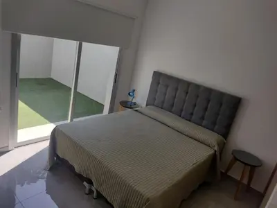 a bed in a bedroom with a large window at Departamento céntrico a cuadras del lago san roque in Villa Carlos Paz