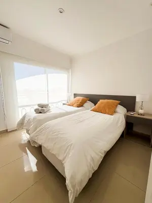 two beds in a room with a large window at Apart France - Dos Dormitorios - Cochera, gim, piscina y spa in Río Cuarto