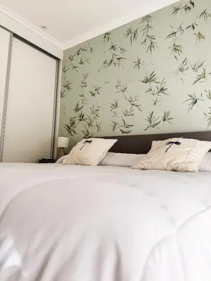 a bedroom with a white bed with a floral wallpaper at Apart France - Dos Dormitorios - Cochera, gim, piscina y spa in Río Cuarto