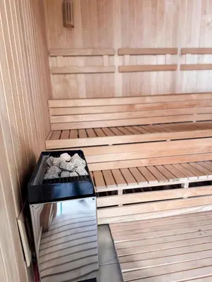 an empty sauna with wooden risers with rocks in it at Apart France - Dos Dormitorios - Cochera, gim, piscina y spa in Río Cuarto