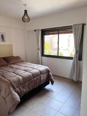 a bedroom with a bed and a large window at Departamento Artigas in Cordoba