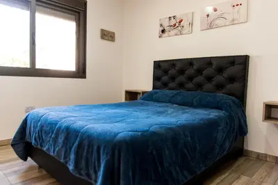 a bedroom with a bed with a blue blanket at Cabañas Imagina in Villa General Belgrano