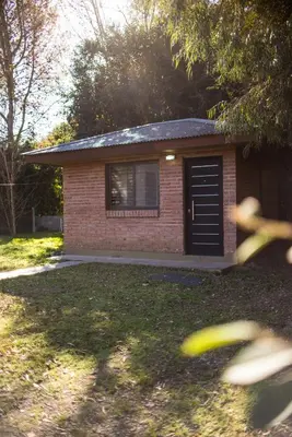 a small brick house with a black garage at Cabañas Imagina in Villa General Belgrano