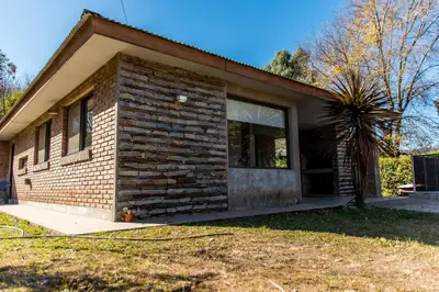 a brick house with a front door and a window at Cabañas Imagina in Villa General Belgrano