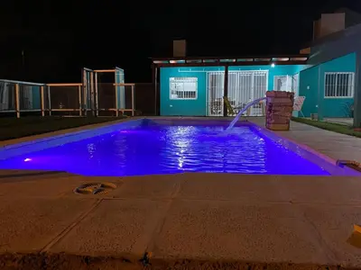a swimming pool with blue lighting in front of a building at Casa con pileta in Río Cuarto