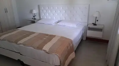 a bedroom with a large white bed and two night stands at Casa con pileta in Río Cuarto