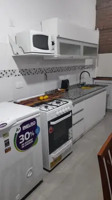 a kitchen with a stove and a microwave at Casa con pileta in Río Cuarto