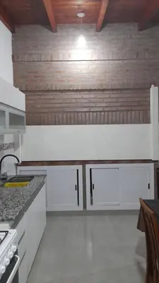 a kitchen with white cabinets and a wooden ceiling at Casa con pileta in Río Cuarto
