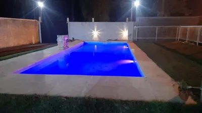 a blue swimming pool at night with lights at Casa con pileta in Río Cuarto