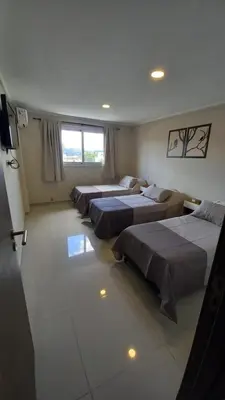 a room with four beds and a television in it at Carcano Temporarios in Villa Carlos Paz