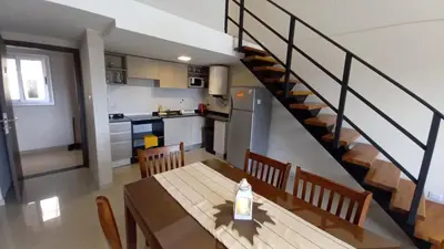 a kitchen and dining room with a table and a staircase at Carcano Temporarios in Villa Carlos Paz