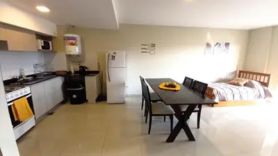 a kitchen and dining room with a table and a bed at Carcano Temporarios in Villa Carlos Paz