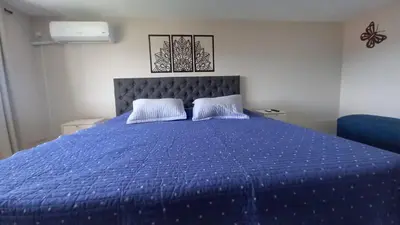 a bed with a blue comforter and two pillows at Carcano Temporarios in Villa Carlos Paz