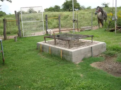 a bench in a field with a horse in the background at Casa de Campo con Pileta - Estancia La Amistad in Villa Santa Cruz del Lago