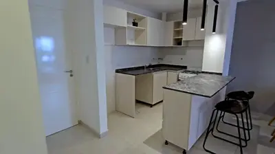 a kitchen with white cabinets and a black counter top at Hostel del carlos in Villa Carlos Paz