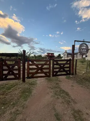 a wooden fence in a field with a sign at L&M Cabañas Villa Yacanto in Villa Yacanto