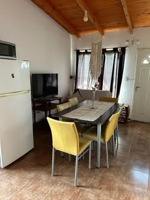 a dining room table with yellow chairs and a white refrigerator at Alma ina in Villa Yacanto