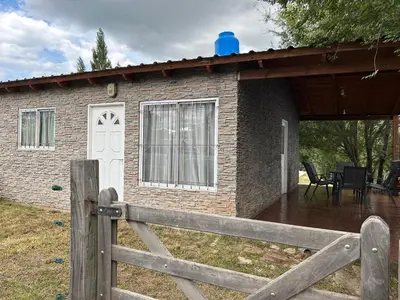 a brick house with a white door and a fence at Alma ina in Villa Yacanto