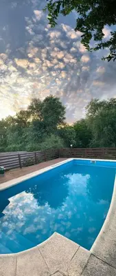 a blue swimming pool with a cloudy sky at Carlos Paz Casa con pileta cerca Río y Centro in Villa Carlos Paz