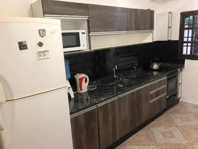 a kitchen with a white refrigerator and a sink at Carlos Paz Casa con pileta cerca Río y Centro in Villa Carlos Paz