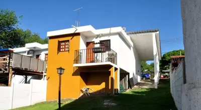 a yellow and white building with a balcony at Carlos Paz Casa con pileta cerca Río y Centro in Villa Carlos Paz