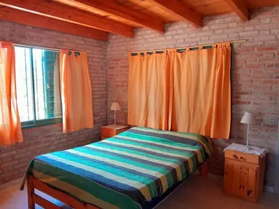 a bedroom with a bed with orange curtains and a window at Bajos de Nono in Nono