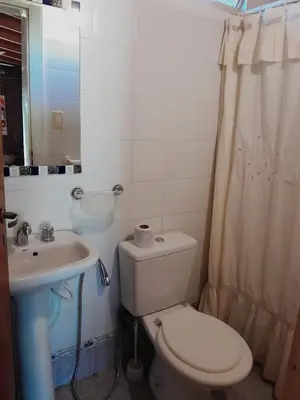 a white bathroom with a toilet and a sink at Bajos de Nono in Nono