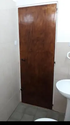 a wooden door in a bathroom with a sink at Postal Serrana 1 in Villa Cura Brochero