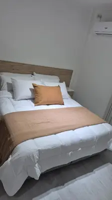 a large white bed with a brown pillow on it at Departamento Céntrico Margarita - Villa Carlos Paz in Villa Carlos Paz