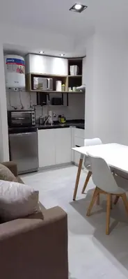 a kitchen with white cabinets and a table in a room at Departamento Céntrico Margarita - Villa Carlos Paz in Villa Carlos Paz