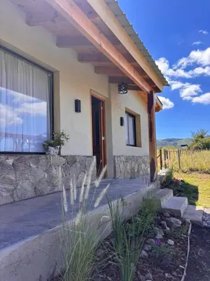 a house with a stone retaining wall and a porch at Las Tacuaritas in Villa Ciudad Parque