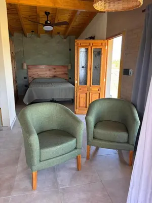 two green chairs in a bedroom with a bed at Las Tacuaritas in Villa Ciudad Parque