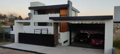 a house with two cars parked in a garage at Homer Renata Goethe 1197 Villa Carlos Paz, Córdoba in Villa del Lago