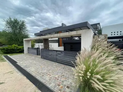 a house with a black roof and a brick patio at Homer Renata Goethe 1197 Villa Carlos Paz, Córdoba in Villa del Lago