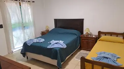 a bedroom with a bed with blue sheets and a window at Bosquesito in Mina Clavero